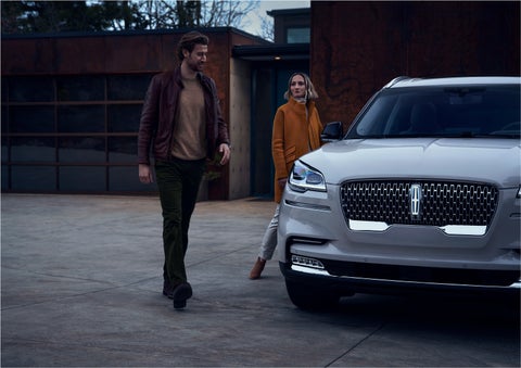 A man and a woman approaching a 2023 Lincoln Aviator® SUV, which illuminates certain lights when they are close | Lexington Park Ford Lincoln in California MD