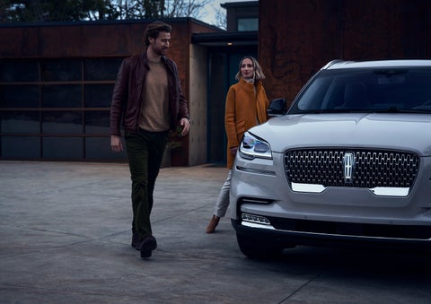 A man and a woman approaching a 2024 Lincoln Aviator® SUV, which illuminates certain lights when they are close | Lexington Park Ford Lincoln in California MD