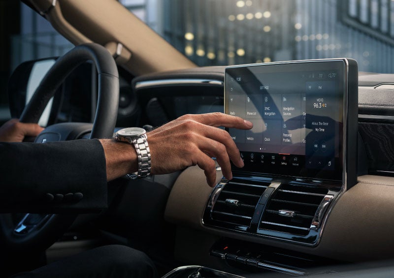 A driver of a 2024 Lincoln Navigator(r) SUV reaches for the center touch screen.