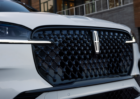 The black grille of a white 2025 Lincoln Aviator® SUV is shown with its fog lights on. | Lexington Park Ford Lincoln in California MD