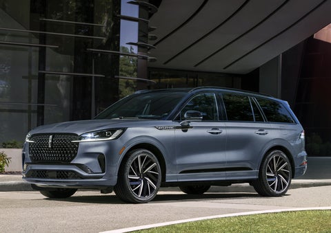 A gray 2025 Lincoln Aviator® SUV is parked outside a modern building showcasing the driver’s side of the vehicle. | Lexington Park Ford Lincoln in California MD