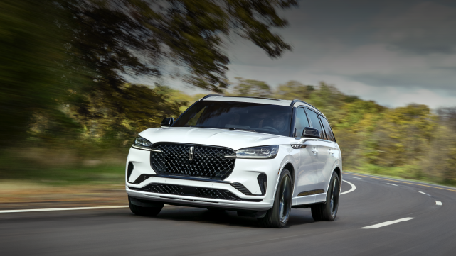 A white 2025 Lincoln Aviator® SUV is being driven down a road lined with trees. | Lexington Park Ford Lincoln in California MD