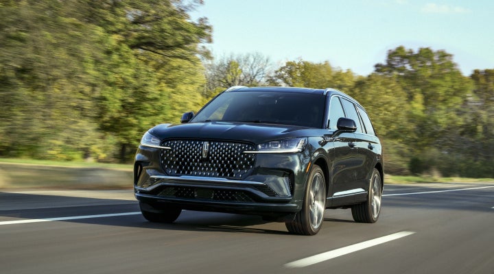 A 2026 Lincoln Black Label™ Aviator® SUV is being driven down a road lined with trees. | Lexington Park Ford Lincoln in California MD