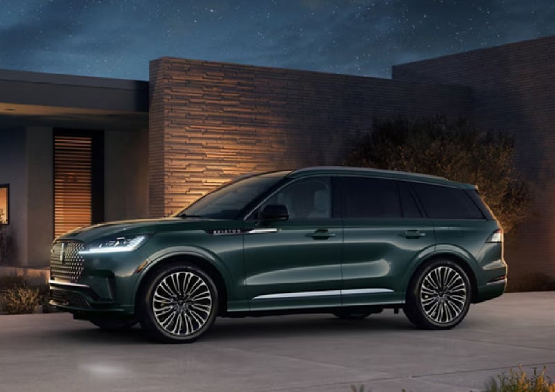 A green 2027 Lincoln Aviator® SUV is parked outside a contemporary home. | Lexington Park Lincoln in California MD
