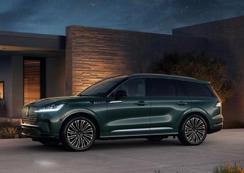 A green 2027 Lincoln Aviator® SUV is parked outside a contemporary home. | Lexington Park Lincoln in California MD