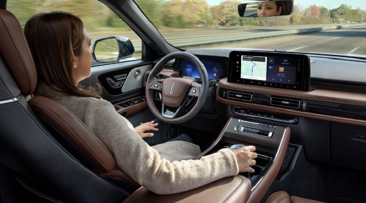 A 2027 Lincoln Aviator® SUV is being driven hands-free on a highway lined with trees. | Lexington Park Lincoln in California MD