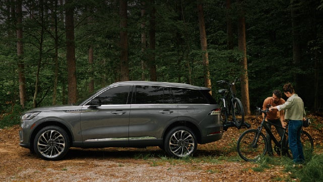 A father and son load e-bikes on a bike rack attached to a 2027 Lincoln Aviator® SUV. | Lexington Park Lincoln in California MD